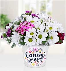 Anneler günü temalı seramik vazo içerisinde beyaz papatya, hüsnüyusuf ve yeşillikler ile hazırlanmıştır.